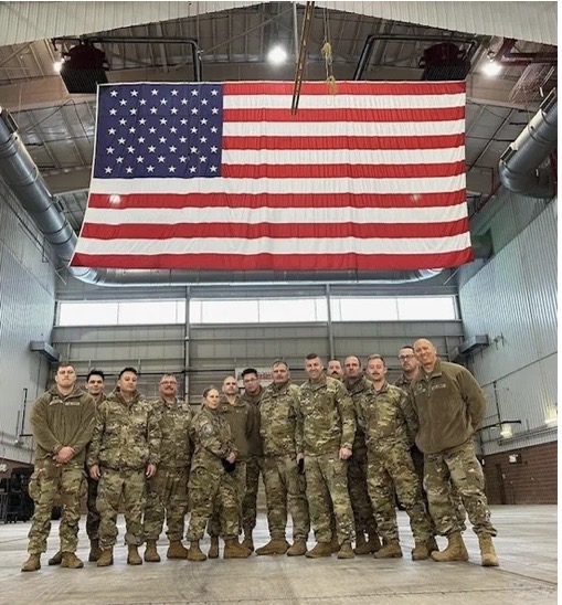 Military team standing under a large American flag